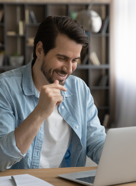 Man smiling while using a laptop